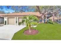 Charming home featuring a two-car garage, well-manicured lawn and mature trees offering a welcoming curb appeal at 2606 Oak Cir, Tarpon Springs, FL 34689