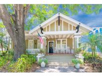 Charming craftsman home featuring a covered front porch, lush landscaping, and an American flag at 705 S Fielding Ave, Tampa, FL 33606