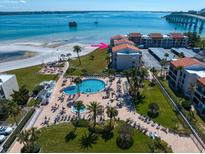 Aerial view of condo resort featuring a pool, palm trees, manicured landscaping, and nearby beach access at 825 S Gulfview Blvd # 208, Clearwater Beach, FL 33767
