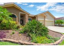 Beautifully landscaped front yard with lush plantings and brick-edged garden beds create inviting curb appeal at 11209 Bloomington Dr, Tampa, FL 33635