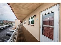 Hallway view of condo unit 303 with a storm door, building number, and view of the parking lot at 3010 59Th S St # 303, Gulfport, FL 33707