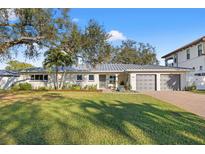 Charming single-story home with a well-manicured lawn, a gray roof and a two car garage at 3961 12Th Ne St, St Petersburg, FL 33703