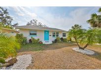 Charming exterior with a blue front door, fresh paint, and tropical landscaping at 6560 5Th S Ave, St Petersburg, FL 33707