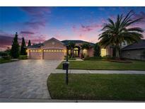 Charming single-story home featuring a three-car garage and a beautifully landscaped front yard with a large palm tree at 2903 Marble Crest Dr, Land O Lakes, FL 34638
