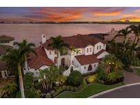 Waterfront home with a red tile roof, a Mediterranean architectural style, and lush tropical landscaping at 705 Riviera Dunes Way, Palmetto, FL 34221