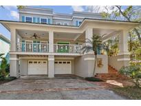 Inviting two-story home featuring a spacious porch, bright blue shutters, and a two-car garage at 2508 W Shell Point Rd, Tampa, FL 33611