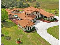 Stunning aerial view of a custom home with a terracotta roof and circular driveway at 11158 Warm Wind Way, Weeki Wachee, FL 34613