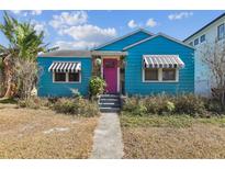 Charming blue home with black and white awnings and vibrant pink front door at 114 S Gunlock Ave, Tampa, FL 33609