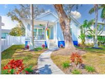 Charming home showcasing a light blue exterior, welcoming porch, and beautifully landscaped yard with stone pathway at 112 17Th E St, Bradenton, FL 34208