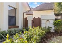 Charming side entrance with wooden gate and beautifully landscaped garden featuring colorful flowers and lush greenery at 14766 Feather Cove Ln, Clearwater, FL 33762