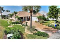 Stunning single-story home showcasing a gorgeous brick driveway, lush landscaping, and mature palm trees at 2359 Emerald Lake Dr, Sun City Center, FL 33573