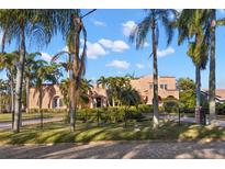 Beautiful home exterior showcasing lush landscaping, a brick street, mature palm trees, and wrought iron fencing at 6935 Date Palm S Ave, St Petersburg, FL 33707