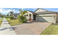 Charming single-Gathering home showcasing a brick-paved driveway and lush front lawn at 13218 Satin Lily Dr, Riverview, FL 33579