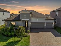 Beautiful single-Gathering home showcasing a three-car garage, brick driveway, and meticulously landscaped front yard at 11717 Navajo Sandstone St, Riverview, FL 33579