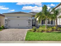 Charming single-story home features a well-manicured lawn, stone accents, and a brick driveway at 32773 Tree Of Life Ave, Wesley Chapel, FL 33543