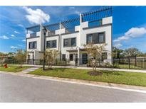 Modern townhome exterior with a black metal fence, green grass, and trellises on the roof at 6207 64Th N Way, Pinellas Park, FL 33781