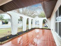 Inviting front porch features decorative columns, flower beds, and red tile flooring at 6718 Ranchwood Loop, New Port Richey, FL 34653