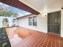 Welcoming front porch with tile flooring, fresh landscaping, and a stylish front door at 6718 Ranchwood Loop, New Port Richey, FL 34653