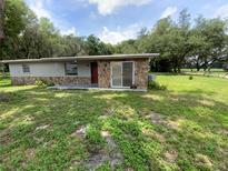 Single story home with stone facade, glass sliding door and partial lawn at 3223 Coats Rd, Zephyrhills, FL 33541