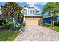 Charming two-story home features stone accents, a well-manicured lawn, and a brick paved driveway leading to a two car garage at 4071 Balcony Breeze Dr, Land O Lakes, FL 34638