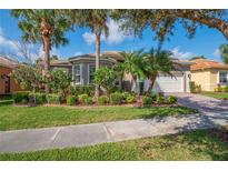 Charming single-story home featuring lush landscaping with palm trees and a well-manicured lawn at 4946 Sapphire Sound Dr, Wimauma, FL 33598