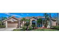 Charming home with a two-car garage, neutral paint, and landscaped yard with mature trees and colorful flowerbeds at 9101 Highland Ridge Way, Tampa, FL 33647