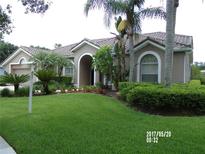 Charming one-story home with a tile roof, arched entryway, lush landscaping, and a vibrant green lawn at 9101 Highland Ridge Way, Tampa, FL 33647