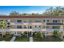 Three-story condo building with balconies, mature trees, and well-maintained landscaping at 2041 Australia W Way # 35, Clearwater, FL 33763