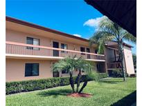 Condo complex featuring a lawn with green landscaping and balconies under a blue sky at 106 Lakeside Ct, Oldsmar, FL 34677