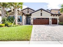 Charming single-Gathering home with a well-manicured lawn, stone facade, and a three-car garage at 21807 Amelia Rose Way, Land O Lakes, FL 34637