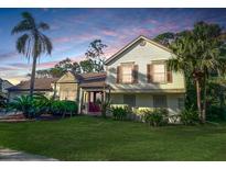 Charming two-story home with a well-manicured lawn, lush tropical landscaping, and a welcoming red front door at 3712 Murray Dale Dr, Valrico, FL 33596