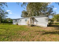 Charming single-story home with gray siding, wooden ramp and stairs, with a large grassy front yard at 8408 Bob Wiggs Ave, Lithia, FL 33547