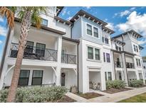 Beautiful three-story townhome featuring a welcoming front porch, balcony and manicured landscaping at 5351 Bridge St # 81, Tampa, FL 33611