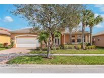 Charming single-story home with a well-manicured lawn, mature trees and attached two car garage at 5062 Stone Harbor Cir, Wimauma, FL 33598