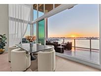 Dining room features a modern table set, floor-to-ceiling windows, and breathtaking water views at sunset at 1020 Sunset Point Rd # 703, Clearwater, FL 33755