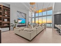 Bright living room with a view, featuring a modern sectional sofa, water view, and a unique chandelier at 1020 Sunset Point Rd # 703, Clearwater, FL 33755