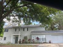 Two-story home with a brick facade and a balcony, complemented by mature trees at 14803 Tulip Dr, Tampa, FL 33613