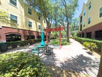 Inviting courtyard with lush landscaping, picnic table with umbrella, and brick-paved walkway at 2010 E Palm Ave # 14206, Tampa, FL 33605