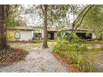 A charming single-story home with a white exterior, black trim, and a beautiful drought-tolerant landscaped yard at 29318 Whipporwill Ln, Wesley Chapel, FL 33543