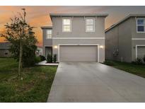 Charming home featuring a two-car garage, manicured lawn, and neutral color palette at sunset at 16126 Sunday Stroll Way, Odessa, FL 33556