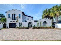Elegant white home showcasing a brick driveway, meticulous landscaping, and mature palm trees at 2113 S West Shore Blvd, Tampa, FL 33629