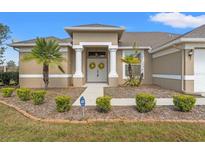 Charming home featuring a covered front entrance with columns and a well-manicured lawn with palm trees at 2250 Long View Cir, Brooksville, FL 34604