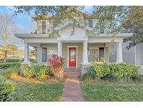 Charming home featuring a welcoming front porch, red door, and beautiful landscaping at 3622 Wiregrass Rd, New Port Richey, FL 34655