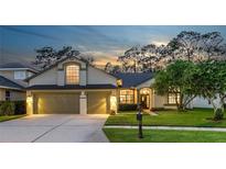 Charming single-Gathering home featuring a well-manicured lawn and a two-car garage against a picturesque evening sky at 12906 Tar Flower Dr, Tampa, FL 33626