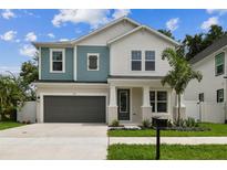 Charming two-story home featuring blue and white accents, a gray garage door, and a well-manicured front yard at 713 W West St, Tampa, FL 33603