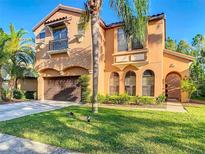 Charming two-story stucco home with a two-car garage, balcony, arched windows, and well-manicured lawn at 8264 Dunham Station Dr, Tampa, FL 33647