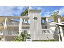 Inviting condo building with multi-level balconies, lush palms, and manicured landscaping at 960 Virginia St # 205, Dunedin, FL 34698