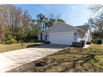 Traditional home featuring an attached two-car garage, spacious driveway, and neatly kept lawn, under a sunny sky at 13305 Whitby Rd, Hudson, FL 34667