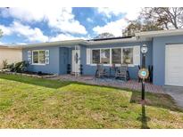 Cozy blue home with a welcoming front porch seating area on a well maintained lawn at 1579 Magnolia Dr, Clearwater, FL 33756