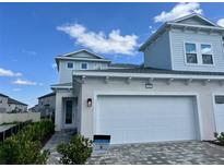 Two-story home showcasing a two-car garage, blue siding, and a well-maintained brick walkway at 31857 Anchor Point Dr, Wesley Chapel, FL 33545